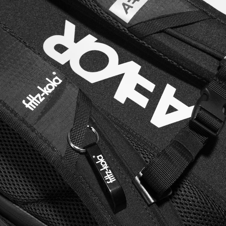 Detailaufnahme der Rückseite des fritz-kola Rucksacks. An dem Schultergurt ist ein Flaschenöffner angehangen. 