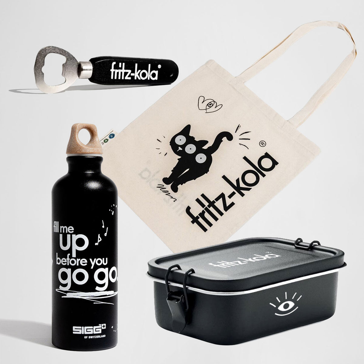 fritz-kola Geschenkset „fritz to go“ auf weißem Hintergrund mit schwarzer „fill me up“-Trinkflasche, schwarzer Lunchbox mit fritz-kola Logo, beigefarbenem Jutebeutel mit schwarzer Wachkatze und fritz-kola Schriftzug sowie einem schwarzen Flaschenöffner mit fritz-kola Logo.