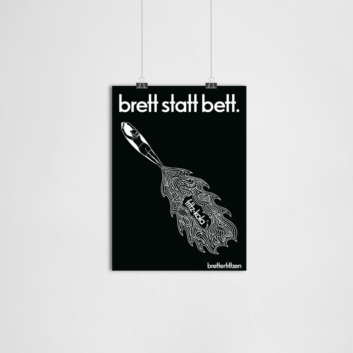 Schwarzes Kunstprint mit weißer Schrift "brett statt bett." oben und "breiterfritzen" unten. In der Mitte ein weißes Surfbrett, aus dem wellenartige Linien fließen, die an Wasser oder Wind erinnern. Das Plakat hängt an zwei silbernen Klammern.